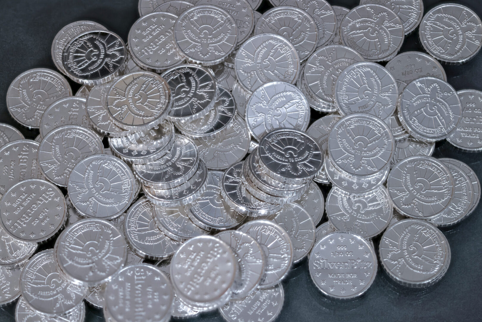 Scattered shiny silver coins on dark background